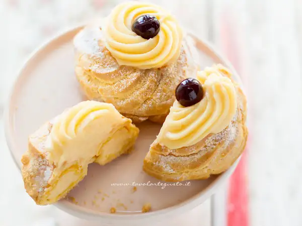 Zeppole di San Giuseppe, dolci soffici con crema pasticcera e ciliegina, perfette per la festa del papà. La ricetta delle zeppole di San Giuseppe è un classico.