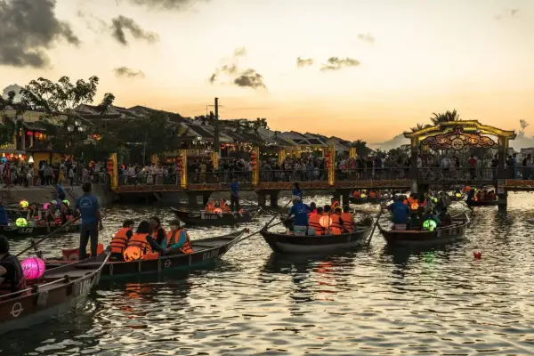 Boote mit bunten Laternen auf einem Fluss in Vietnam bei Sonnenuntergang. Ein toller Tipp für deine Vietnam Reise!