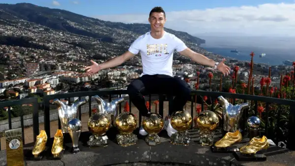 Cristiano Ronaldo z dumą prezentuje swoje liczne trofea, w tym Złote Piłki, na tle malowniczego krajobrazu Madery, swojego rodzinnego domu.