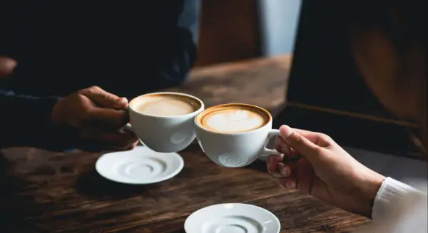 Dos tazas de café humeante, una con arte latte. El café es bueno para la concentración y el disfrute.
