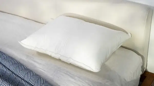 A plush white pillow rests on a neatly made bed, perfect for a comfortable night's sleep, especially for those who prefer to sleep on their stomach.