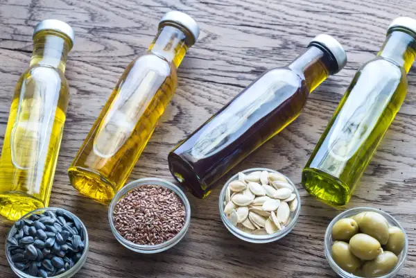 Bottiglie di olio e ciotole con semi di girasole, semi di lino, semi di zucca e olive. Quale sarà il miglior olio per friggere?