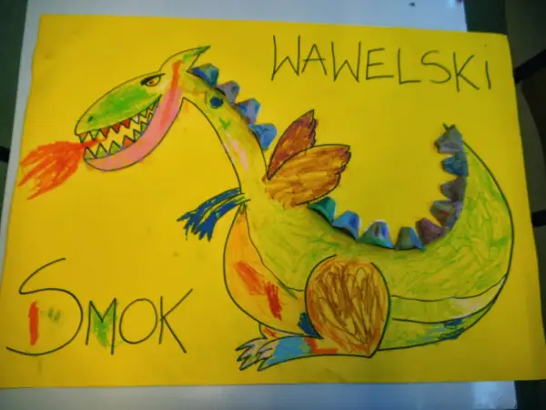 Kolorowa praca plastyczna przedstawiająca zielonego smoka wawelskiego ziejącego ogniem. Napisy "SMOK" i "WAWELSKI" dopełniają dzieło.