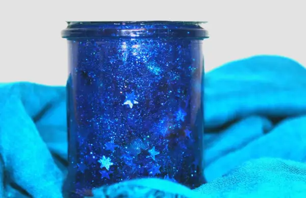 Barattolo della calma blu scintillante con stelle cadenti, avvolto in un tessuto turchese.