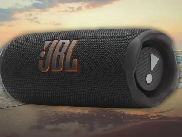 Enceinte JBL noire sur une plage. Découvrez comment fonctionne une enceinte JBL pour une expérience sonore immersive, même en extérieur.