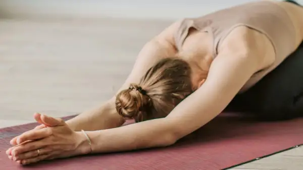 Une femme en posture de yoga, bras tendus, sur un tapis. Un moment pour apprendre comment s'apaiser.