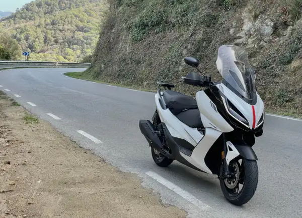 Scooter Zontes blanca en carretera sinuosa. Opiniones sobre motos Zontes: diseño moderno y ágil para rutas de montaña.