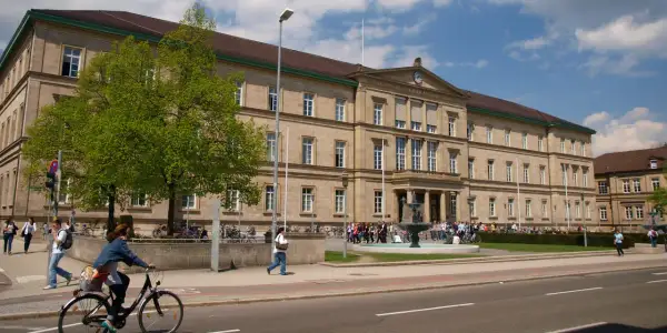 Großes Universitätsgebäude mit Brunnen und Studenten. Hier kann man Zahnmedizin studieren.