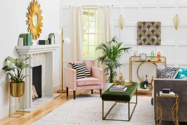 A living room with a pink armchair, gold accents, and a fan pattern artwork, showcasing what is art deco style with its geometric shapes and luxurious feel.