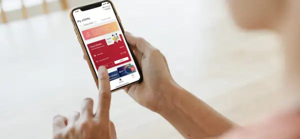 Osoba korzysta z aplikacji Airalo na telefonie, pokazując, jak działa usługa eSIM. Widoczne są aktywne pakiety danych i opcja doładowania.