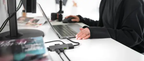Praca zdalna i turystyka w jednym. Ktoś planuje podróż, przeglądając oferty na laptopie, podłączonym do hubu USB.