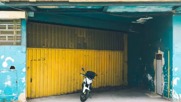 Moto aparcada frente a una cochera con puerta amarilla, se puede aparcar en una cochera sin vado.