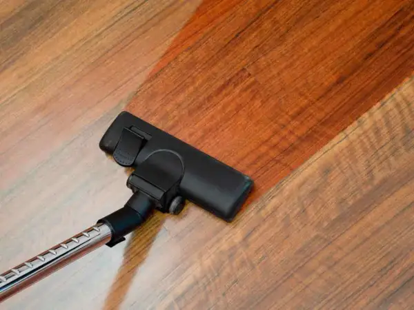 Cabezal de aspiradora limpiando suelo laminado. El suelo laminado se ve brillante y limpio tras pasar la aspiradora.