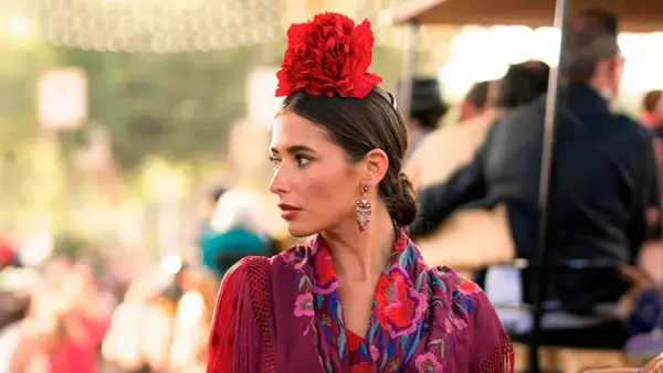 Mujer con flor flamenca en su pelo corto, pendientes llamativos y mantón bordado.