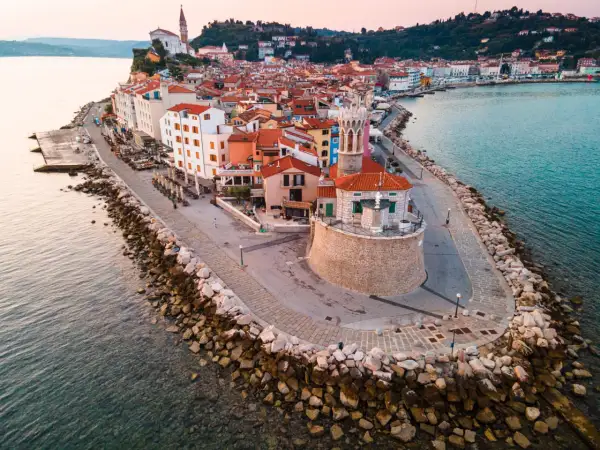 Piran plaża: malownicze miasteczko na półwyspie, z kolorowymi domami, kamienną promenadą i wieżą kościelną górującą nad Adriatykiem.