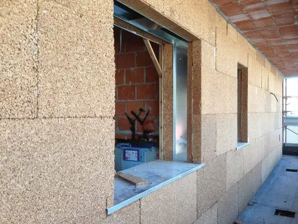 Blocchi di sughero, il miglior isolante termico naturale, rivestono le pareti di un edificio in costruzione, con aperture per finestre.