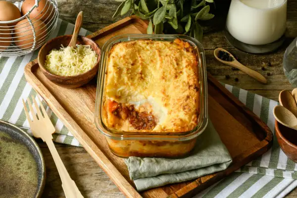 Un delicioso pastel de carne gratinado, listo para servir. Acompañado de queso rallado, huevos y especias.