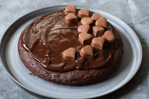 En saftig fransk chokladtårta täckt med chokladglasyr och dekorerad med små chokladhjärtan.
