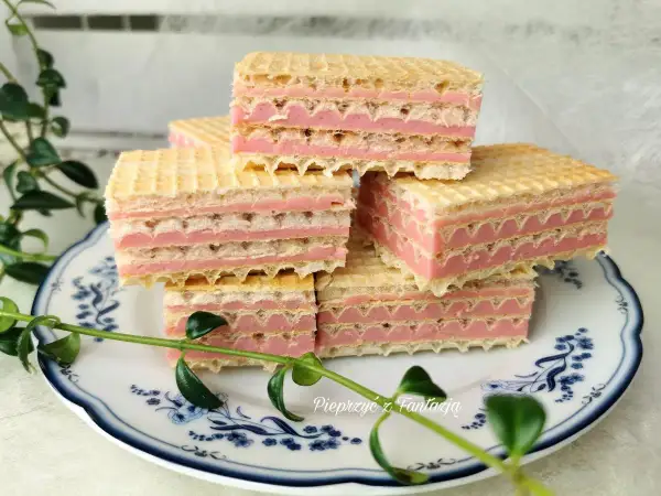 Słodkie wafle z mlekiem w proszku, przełożone różowym kremem, ułożone na talerzyku z niebieskimi wzorami.