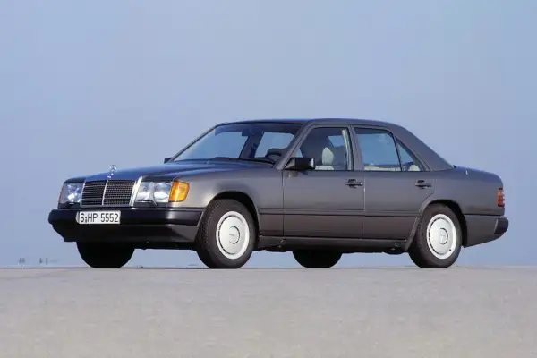 Szary Mercedes-Benz W124, symbol najbardziej niezawodnych samochodów, stoi na pustej drodze.