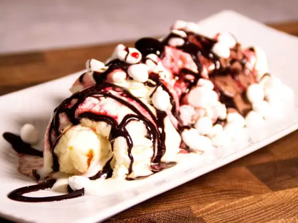 En läcker banana split med tre kulor glass, chokladsås, marshmallows och körsbär.