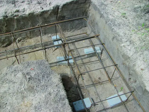 Zbrojenie wieńca w narożu fundamentu, gotowe do zalania betonem. Stalowe pręty tworzą solidną konstrukcję.