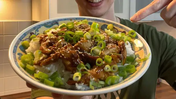 Leckeres Hähnchen Teriyaki Rezept: saftiges Hähnchen in Teriyaki-Sauce auf Reis, garniert mit Frühlingszwiebeln und Sesam.