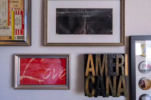 Ściana z obrazami: bilety na koncert, ręcznie pisany list, obraz z napisem "Love" i dekoracja "AMERICANA".