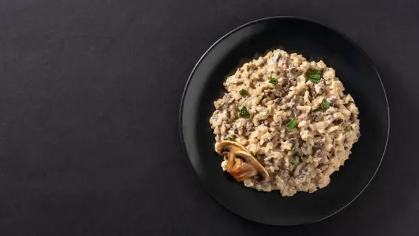 Un crémeux risotto aux champignons, garni de persil frais et d'une tranche de champignon. Un délice végétarien.