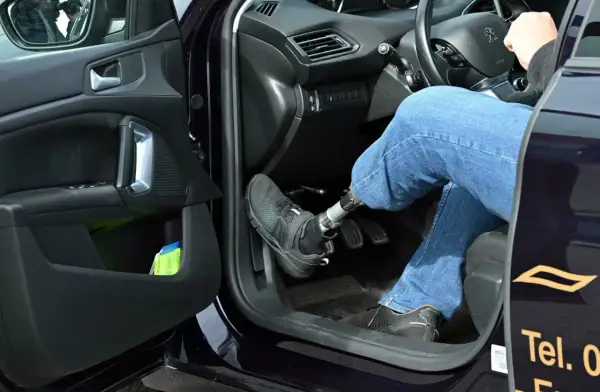 Autofahren mit Orthese links: Person mit Prothese am linken Bein bedient Automatik-Auto.