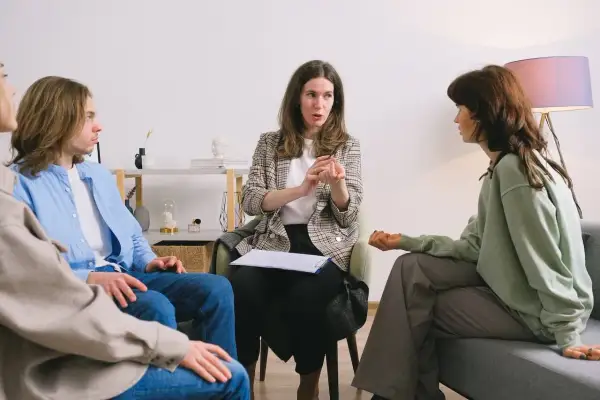 Grupa osób na sesji terapeutycznej z terapeutką uzależnień.