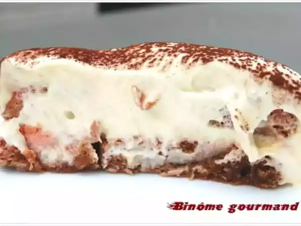 Tranche de tiramisu crémeux, parsemé de cacao, avec des morceaux de biscuit rose. Un délice !