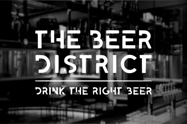 Il logo "The Beer District" su uno sfondo sfocato di un locale con spillatori di birra. Un invito a "bere la birra giusta".