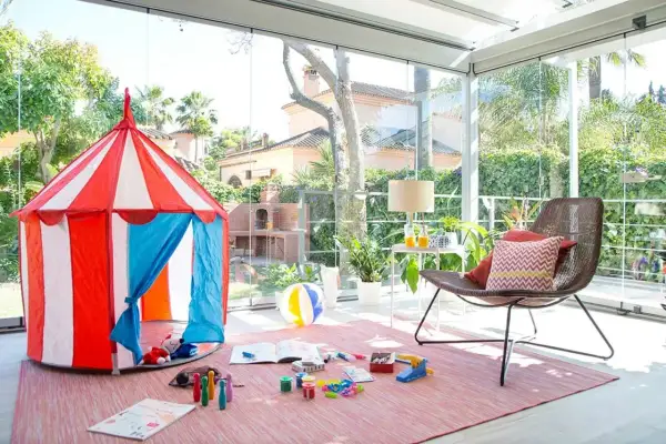 Tienda de circo y juguetes para disfrutar de juegos de patio en un espacio acristalado con vistas al jardín.