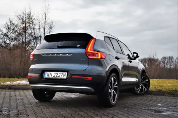 Tylny widok na ciemnoszary Volvo XC40 T3 z białym dachem, zaparkowany na brukowanej nawierzchni.