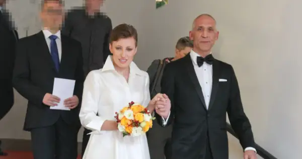 Szczęśliwa para młoda, Maciej i jego żona, idą schodami. Ona w białej sukni z bukietem, on w eleganckim smokingu.