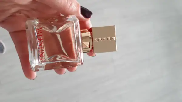 Elegancki flakon Valentino Voce Viva 100ml w dłoni, z charakterystycznym złotym korkiem ozdobionym ćwiekami.