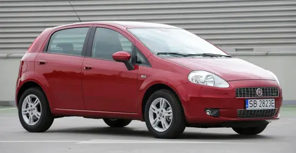 Czerwony Fiat Grande Punto, przód. Wymiana żarówki w reflektorze przednim jest prosta.