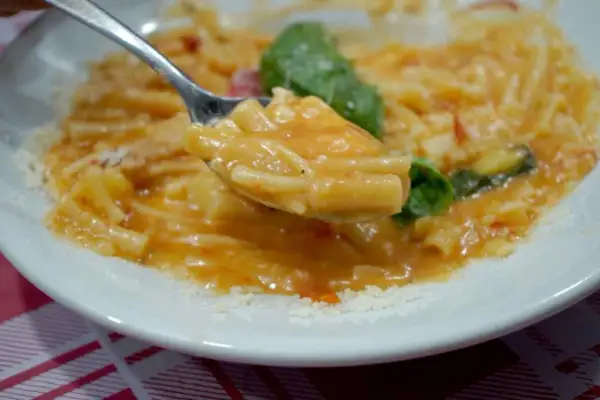 Un cucchiaio di pasta con patate cremosa, condita con basilico fresco e parmigiano grattugiato.