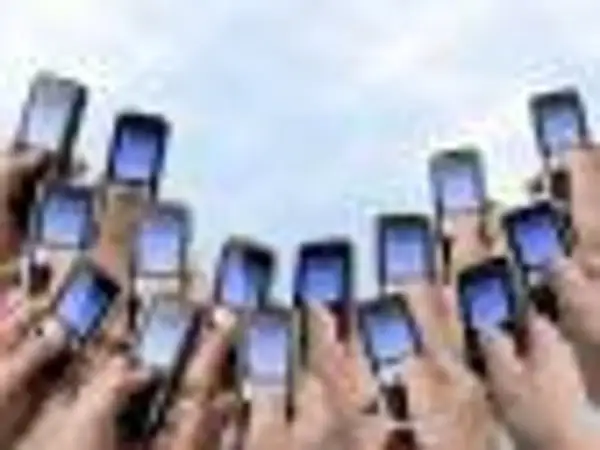 Ręce trzymają telefony komórkowe, gotowe do wysłania pustego SMS-a na loterię.