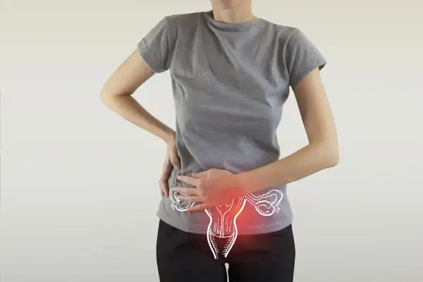 Donna con mani sull'addome, evidenziato un disegno dell'utero con aree rosse. Possibili cause di ovulazione dolorosa.