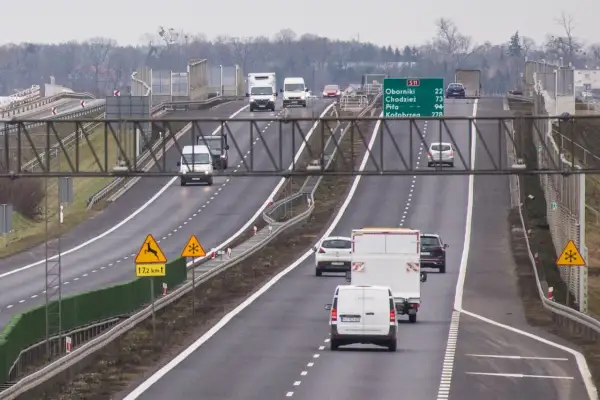 Ruch na drodze S11 Kórnik-Jarocin. Samochody i furgonetki jadą w kierunku Kołobrzegu. Znaki ostrzegają przed dzikimi zwierzętami i śliską nawierzchnią.