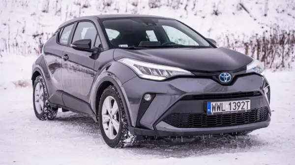 Szary Toyota C-HR Hybrid na śniegu, gotowy na zimowe wyzwania.
