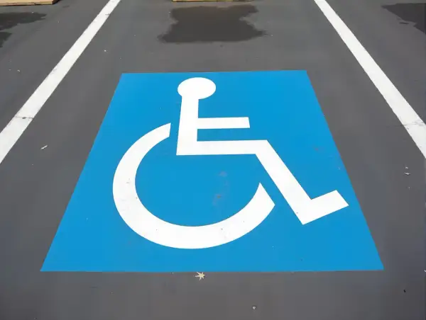 Symbole de fauteuil roulant blanc sur fond bleu, marquant une place de stationnement réservée. Une amende place handicapé est une infraction.