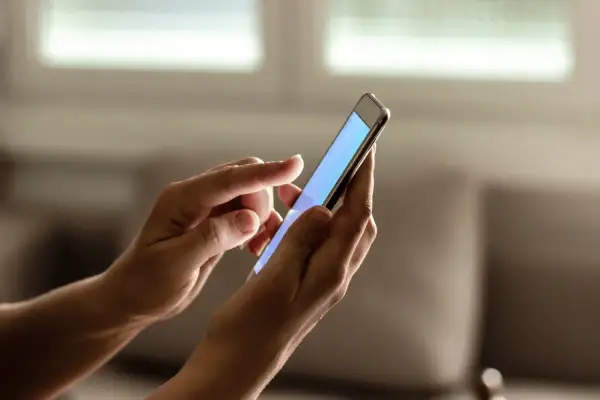 Dłonie trzymają smartfon, na którym można sprawdzić ile lat ma telefon.