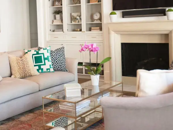 A sofa with pillows showcasing mixing patterns: a fawn print, a bold green geometric, and a black and white ikat.