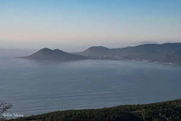 Vista panorámica de la costa gallega con el monte Enxa destacando sobre el mar azul.
