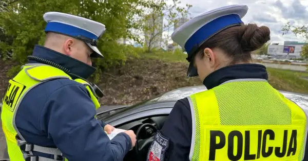 Policjanci w kamizelkach odblaskowych sprawdzają dokumenty, być może wystawiają mandaty za prędkość.