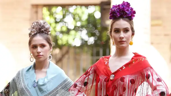 Dos jóvenes con maquillaje flamenca, flores en el pelo y mantones de seda.