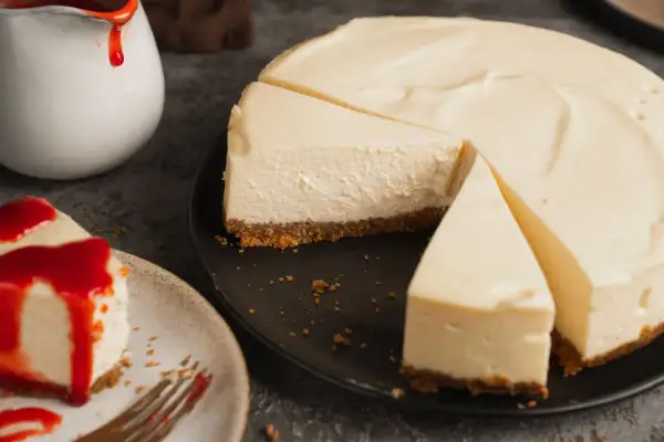 Ein cremiger ny cheesecake, auf einem Teller mit rotem Fruchttopping und ein weiterer auf einem schwarzen Teller, bereit zum Genießen.